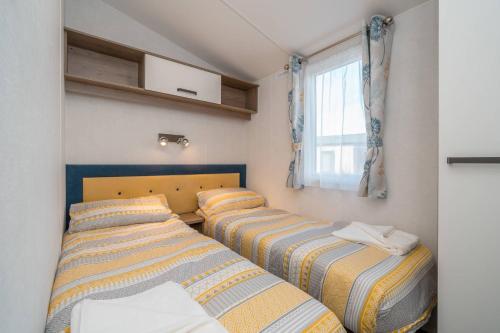 three beds in a small room with a window at Lisa Marie-Luxury Caravan-Seton Sands-8 Berth in Port Seton