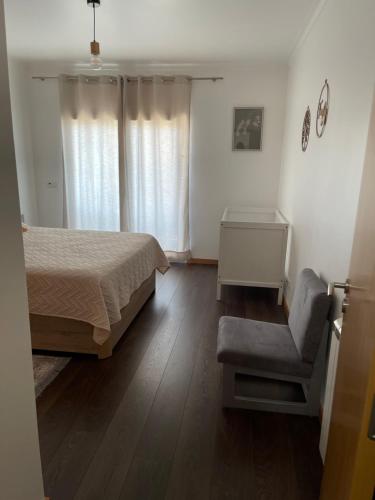 a bedroom with a bed and a chair at GARDEN & BEACH HOUSE in Figueira da Foz