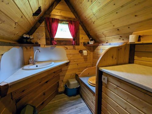 une salle de bain avec un lavabo et des toilettes dans une cabine dans l'établissement Escapade Romantique: Cabane avec Terrasse Panoramique, Poêle à Bois et Éclairage Multicolore - FR-1-589-441, à Ferdrupt