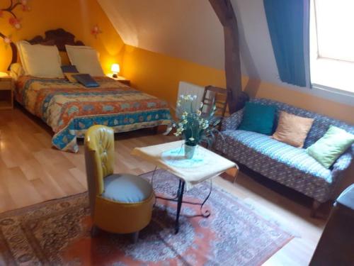 a bedroom with a bed and a couch and a table at Charme et Authenticité en Forêt Maine Normandie : Demeure Rénovée avec Jardin, Idéale pour Séjour Détente - FR-1-410-186 in Crissé