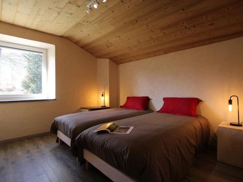 a bedroom with two beds with red pillows and a window at Charmante maison en pierre près du Lac de Lavalette, idéale pour randos, nature et détente totale - FR-1-582-43 in Saint-Jeures