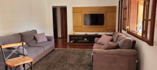 Sala de estar con 2 sofás y TV en Casa Maciel, en São Thomé das Letras