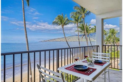 a table on a balcony with a view of the beach at KIHEI BEACH, #406^ condo in Kihei