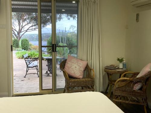 a bedroom with a bed and chairs and a sliding glass door at Midgee Cottage in Mudgee
