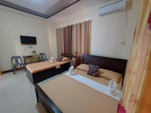 ein Hotelzimmer mit 2 Betten und einem TV in der Unterkunft Rainbow Pension House in Dipolog City