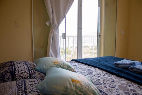 ein Schlafzimmer mit einem Bett mit Kissen und einem Fenster in der Unterkunft Casa do Farol in Itapoa