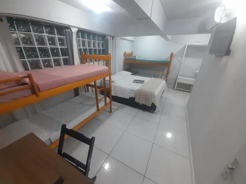 a room with two beds and a table and a window at Pousada cafe com margarida 150 metros do mar rua do calçadao da central in Balneário Camboriú
