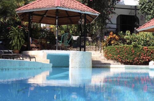 a swimming pool with an umbrella and a table and chairs at The Scarlet Villas in Ojochal