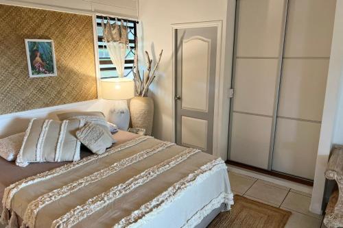 a bedroom with a large bed and a mirror at BUNGALOW F2 Atypical local style in Faaa
