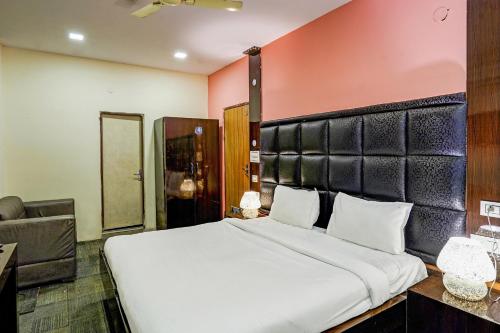 a bedroom with a large white bed with a black headboard at Collection O RIVERIA RESORT in Noida