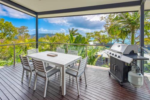 a deck with a table and chairs and a grill at Pinnacle Apartments on Hamilton Island by HIHA in Hamilton Island