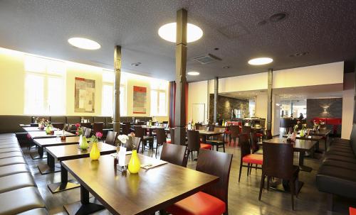 a restaurant with wooden tables and chairs and tablesearcher at Mille Stelle Hotel in Eggenstein-Leopoldshafen