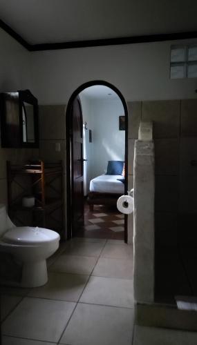 a bathroom with a toilet and a bed in a room at The Scarlet Villas in Ojochal
