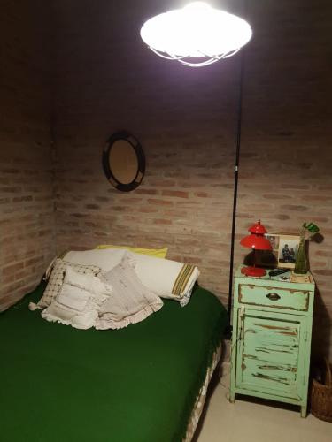 1 dormitorio con cama, lámpara y mesita de noche en Dormitorio con baño privado, cocina y living compartido con pileta en country en Pergamino