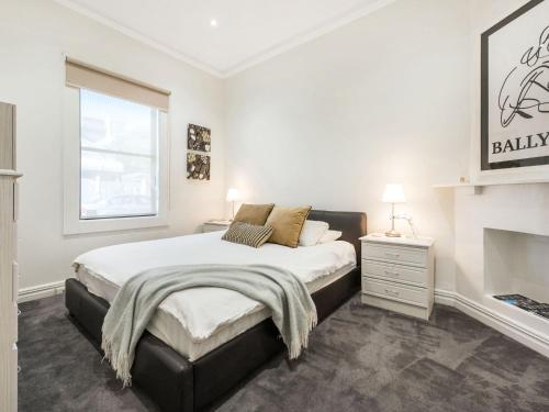 a white bedroom with a bed and a fireplace at Walk to the MCG - Renovated House with back yard in Melbourne