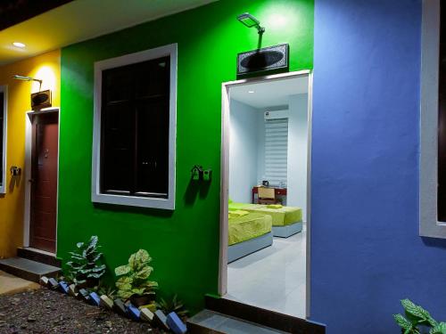 a room with a green wall and a mirror at The Marak Village KB - Mini Homestay in Kota Bharu