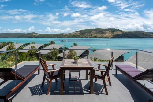 a balcony with a table and chairs and the ocean at Yacht Club Villas on Hamilton Island by HIHA in Hamilton Island