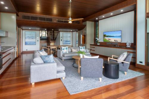 a living room with a couch and chairs and a tv at Yacht Club Villas on Hamilton Island by HIHA in Hamilton Island