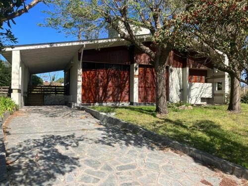 una casa con un garaje con un árbol frente a Losgumitas.3 en Villa Gesell