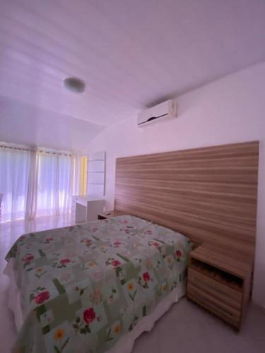 1 dormitorio con 1 cama grande y cabecero de madera en Casa de praia 250 metros da praia, en Aracaju