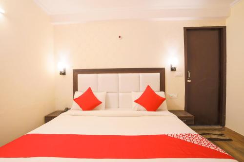 a bedroom with a large bed with red pillows at OYO Flagship Hotel Lazeeno in Faridabad