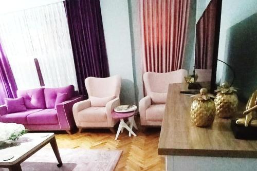 uma sala de estar com cadeiras roxas e cor-de-rosa e uma mesa em Grand appartement 21 em Istambul