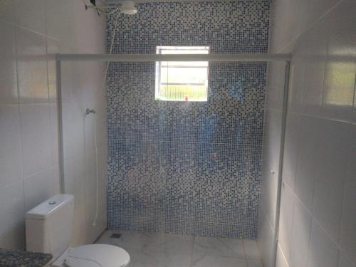 a bathroom with a shower with a toilet and a window at Refúgio dos Moreiras in Monteiro Lobato