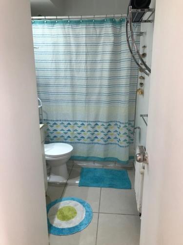 a bathroom with a toilet and a shower curtain at Condominio PLaza Club in Temuco