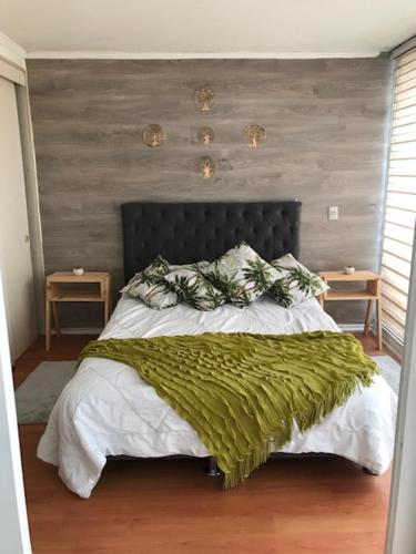 a bedroom with a large bed with a green blanket at Condominio PLaza Club in Temuco