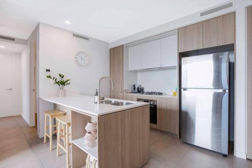 a kitchen with a refrigerator and a counter top at Gabba Oasis:Luxury 3BRM Apt Pool in Brisbane