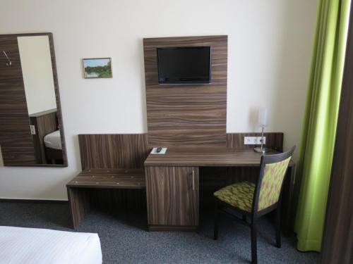 a room with a desk with a television and a chair at Hotel-Restaurant Zum Stern in Baumholder