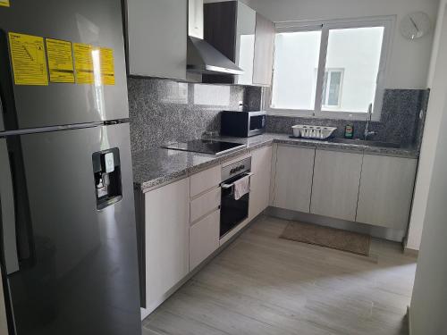 a kitchen with a stainless steel refrigerator and cabinets at Hard Rock Punta Cana Coral Bay II apartment 2 BR by BTC Crypto Group in Punta Cana