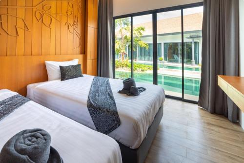 2 camas en una habitación con vistas a la piscina en Tajh Pool Villas, en Chalong 