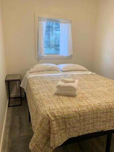 a bed with a blanket and a window at Downtown Hilo Apt L in Hilo