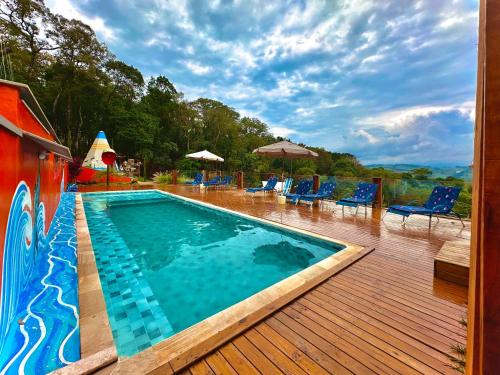 a swimming pool on a wooden deck with chairs at Sequoia Casa na Árvore, Vila Mágica in Bueno Brandão