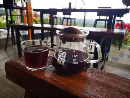 a glass jar of coffee sitting on a wooden table next to a drink at Balelangga Bed & Breakfast in Sapit