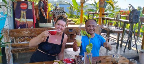 un homme et une femme tenant des boissons à une table dans l'établissement Balelangga Bed & Breakfast, à Sapit