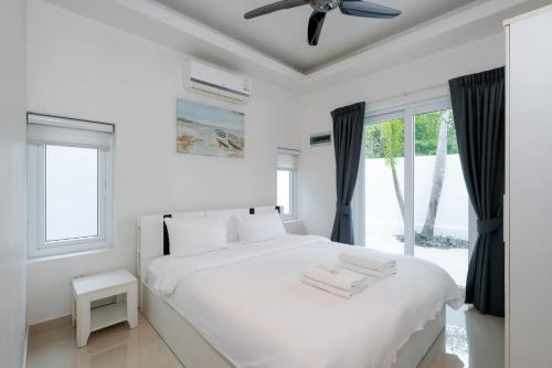 a white bedroom with a bed and a ceiling fan at Orchid Paradise Homes OPV 210 in Hua Hin