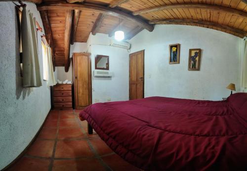 a bedroom with a red bed and a wooden ceiling at Cabañas Budapest in Capilla del Monte