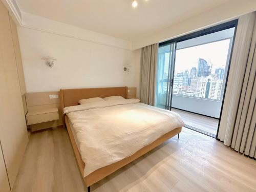 um quarto com uma cama grande e uma janela grande em ZHome-Modern 3 bedrooms apartment - near NanJing Road em Xangai