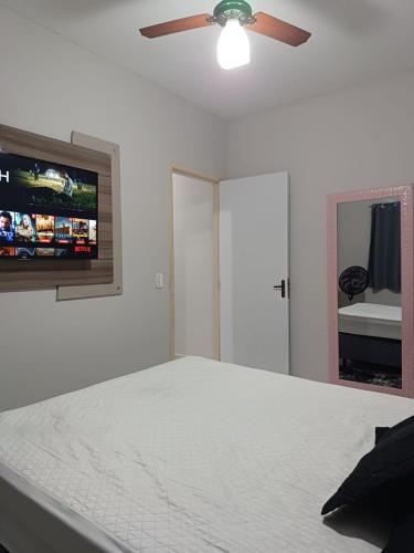 een witte slaapkamer met een bed en een plafondventilator bij Apartamento encantador 22 in Ubatuba