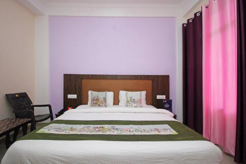 a bedroom with a large bed with pink curtains at OYO Hotel Chandni in Dharmsala