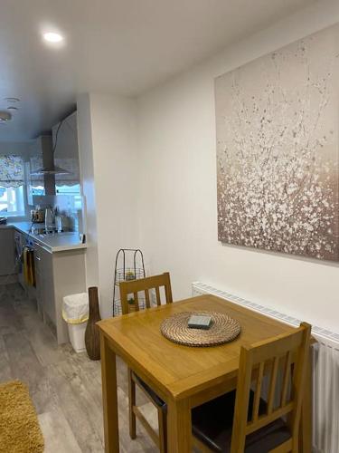 a table and chairs in a kitchen with a painting on the wall at The Lions Den flat at the red lion public house. in Newbridge