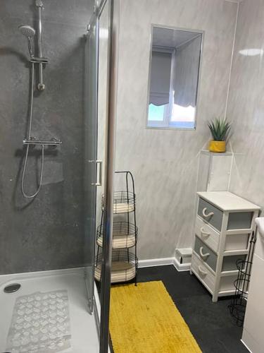 a bathroom with a shower with a yellow rug at The Lions Den flat at the red lion public house. in Newbridge