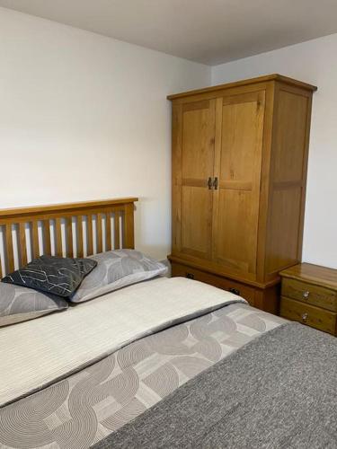 a bedroom with a bed and a wooden cabinet at The Lions Den flat at the red lion public house. in Newbridge