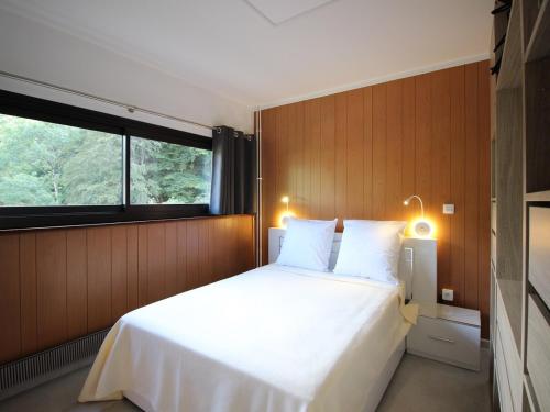 une chambre avec un grand lit blanc avec une fenêtre dans l'établissement Mont-Dore: 4 pers, proche centre, WIFI, parking, T2 au calme - FR-1-608-253, à Le Mont-Dore