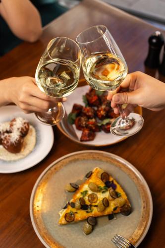 a table with two glasses of wine and a slice of pizza at West Hotel Sydney, Curio Collection by Hilton in Sydney