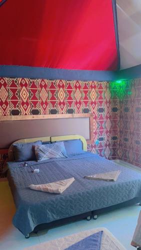a bedroom with a bed with a red and green ceiling at Shakria Bedouin Life Camp in Wadi Rum