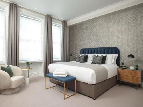 a bedroom with a king sized bed and a chair at Uber Mayfair Luxury Apartment in London
