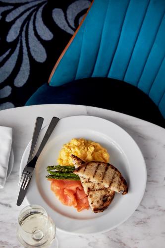 a plate of food with eggs and meat on a table at West Hotel Sydney, Curio Collection by Hilton in Sydney